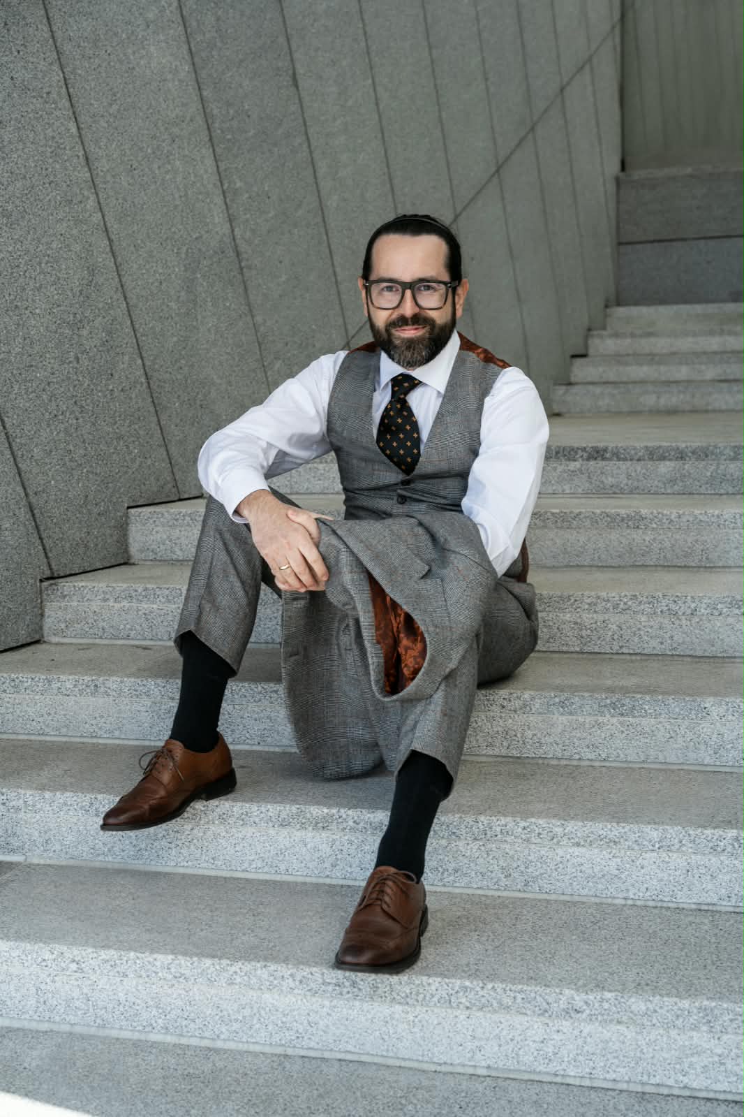 Dariusz Fink-Finowicki siedzący na schodach, uśmiechnięty, patrzy w obiektyw